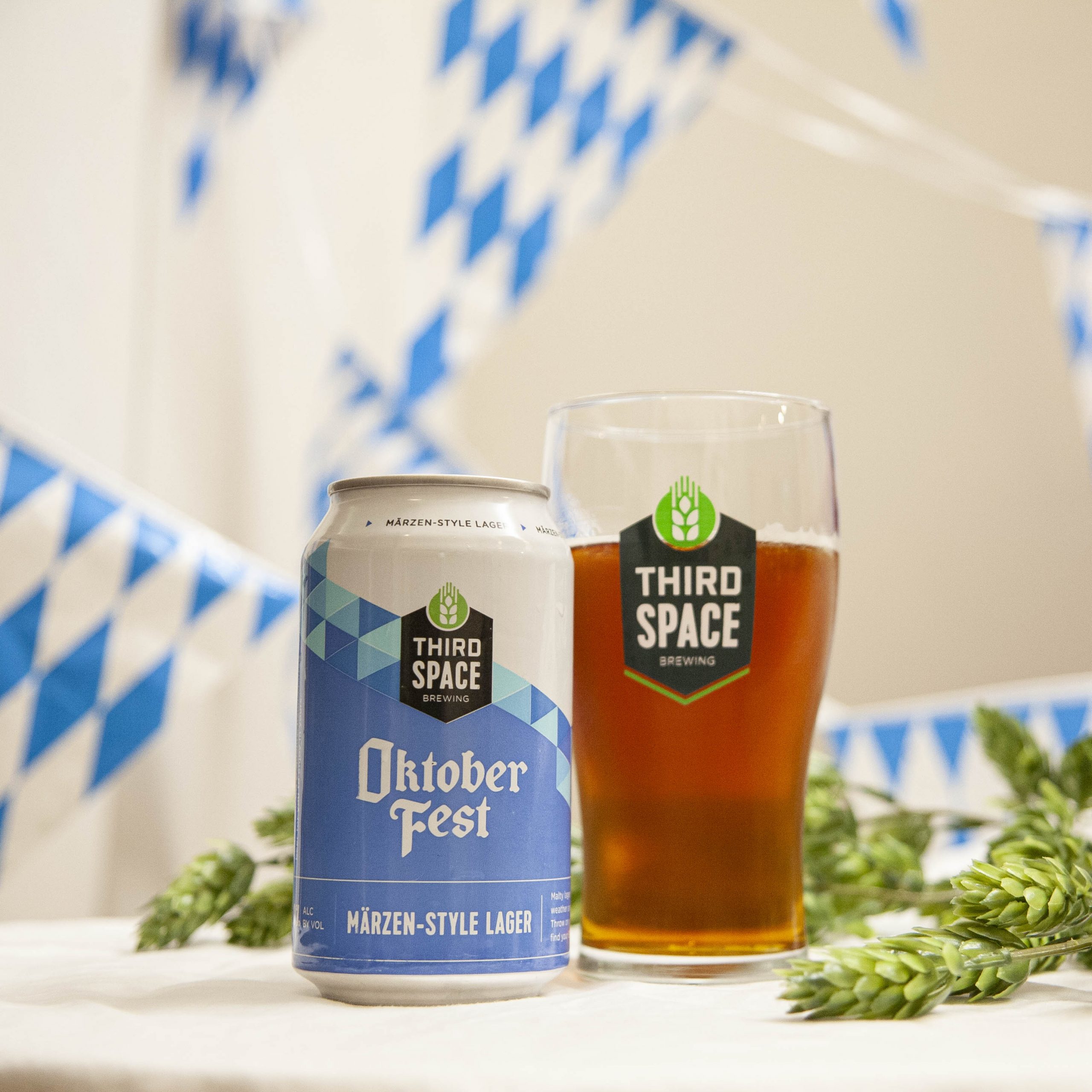 Third Space's Oktoberfest is poured into a branded glass, amidst hop cones and blue and white bunting.