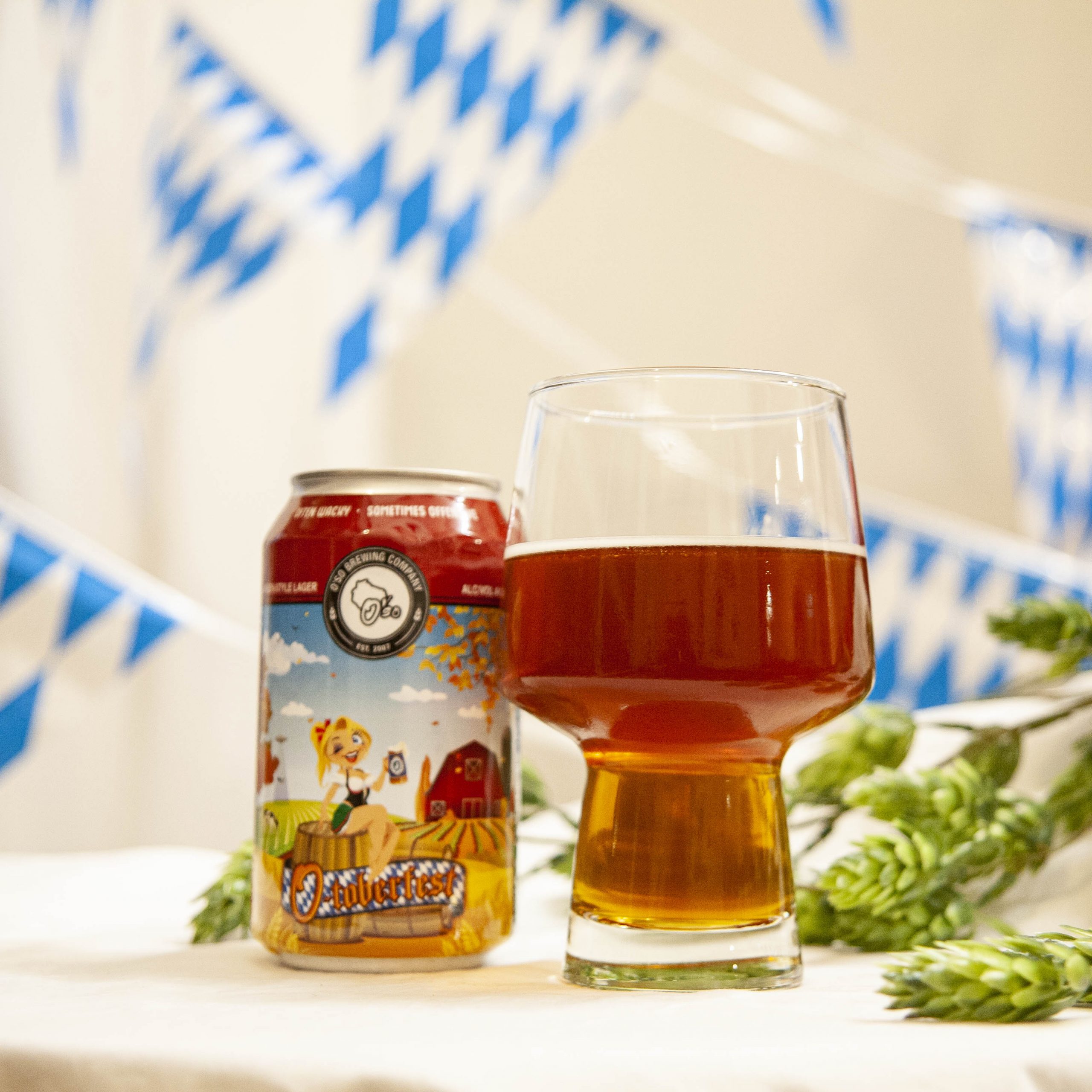 O'so's O-Toberfest is poured into a funky beer glass, amidst hop cones and blue and white bunting.