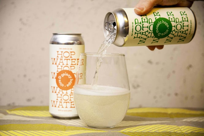 A can of Fair Stat Co-op Hop Water is poured into a stemless wineglass.