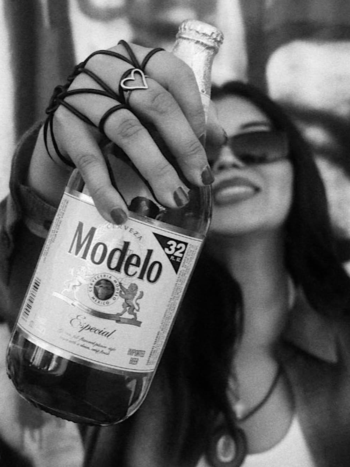 woman with sunglasses holding a caguama bottle of modelo especial in front of her