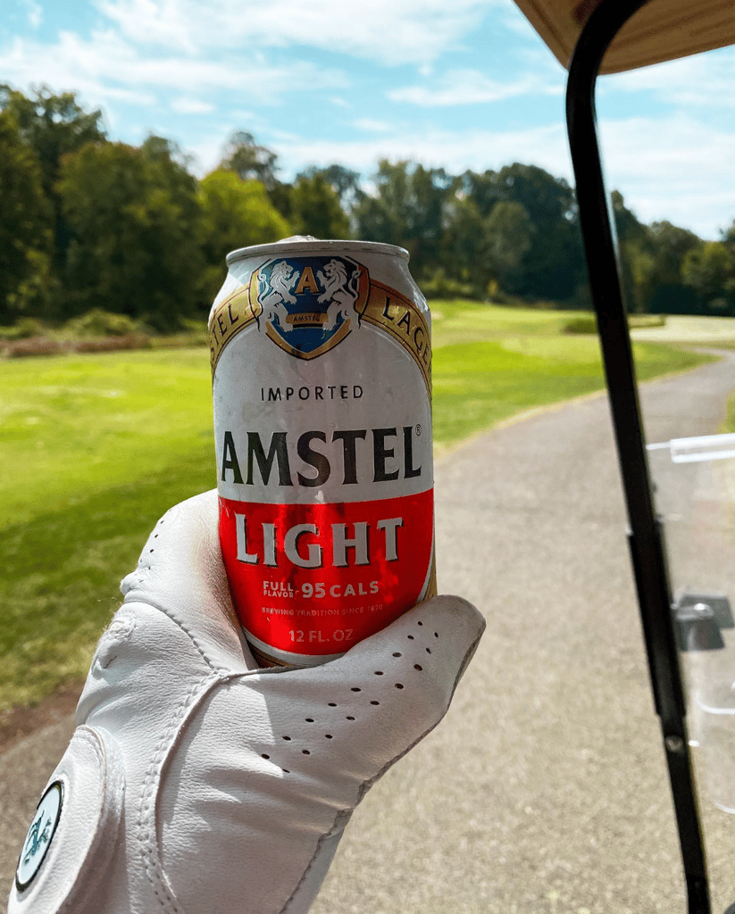 A hand holding an Amstel Light beer can.