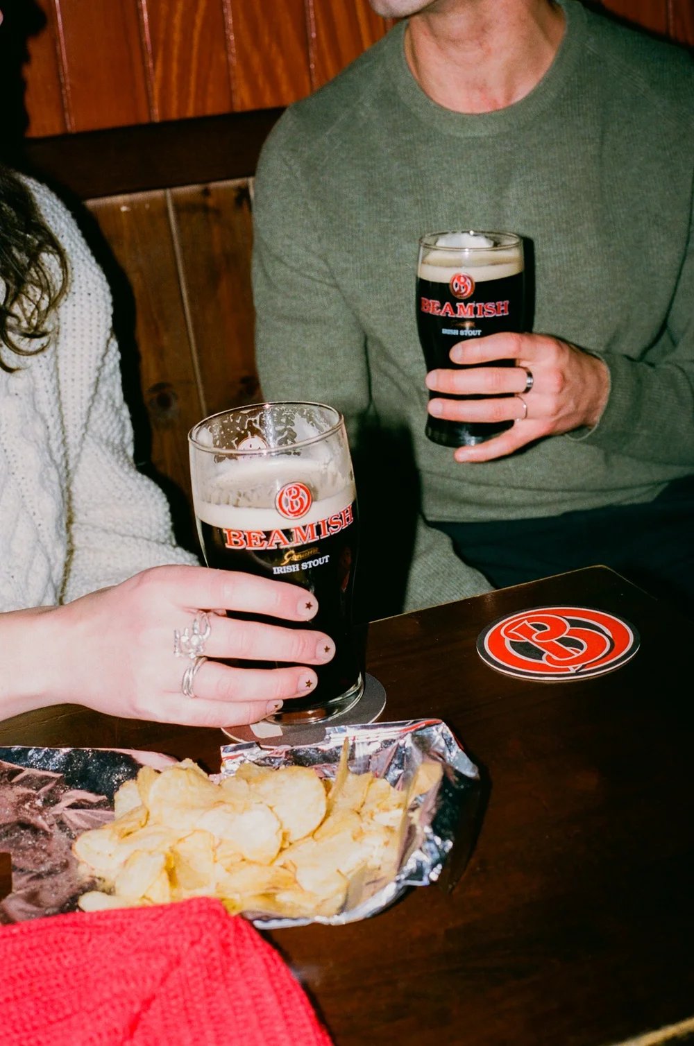 Man and woman holding Beamish Irish Stout glasses with chips