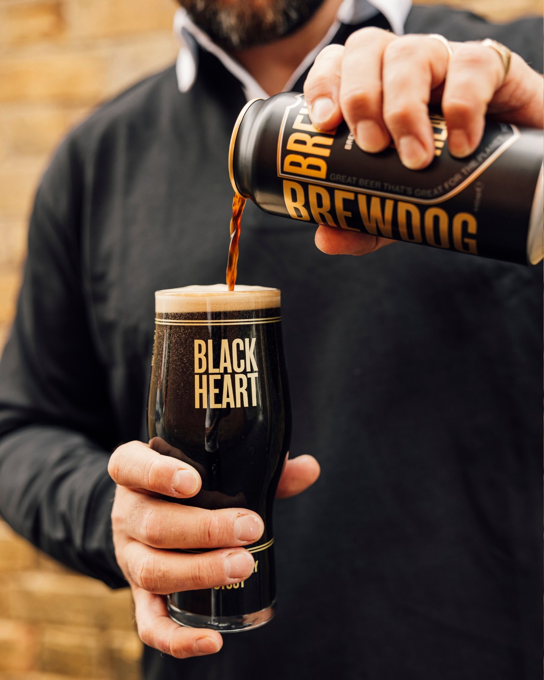 Rugby player pouring BrewDog black heart stout into glass.