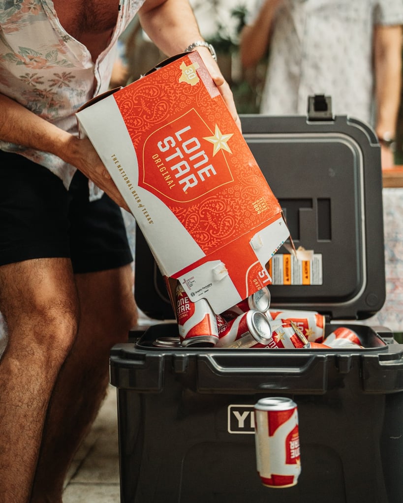 person roughly loading a cooler-full of lone star beer cans