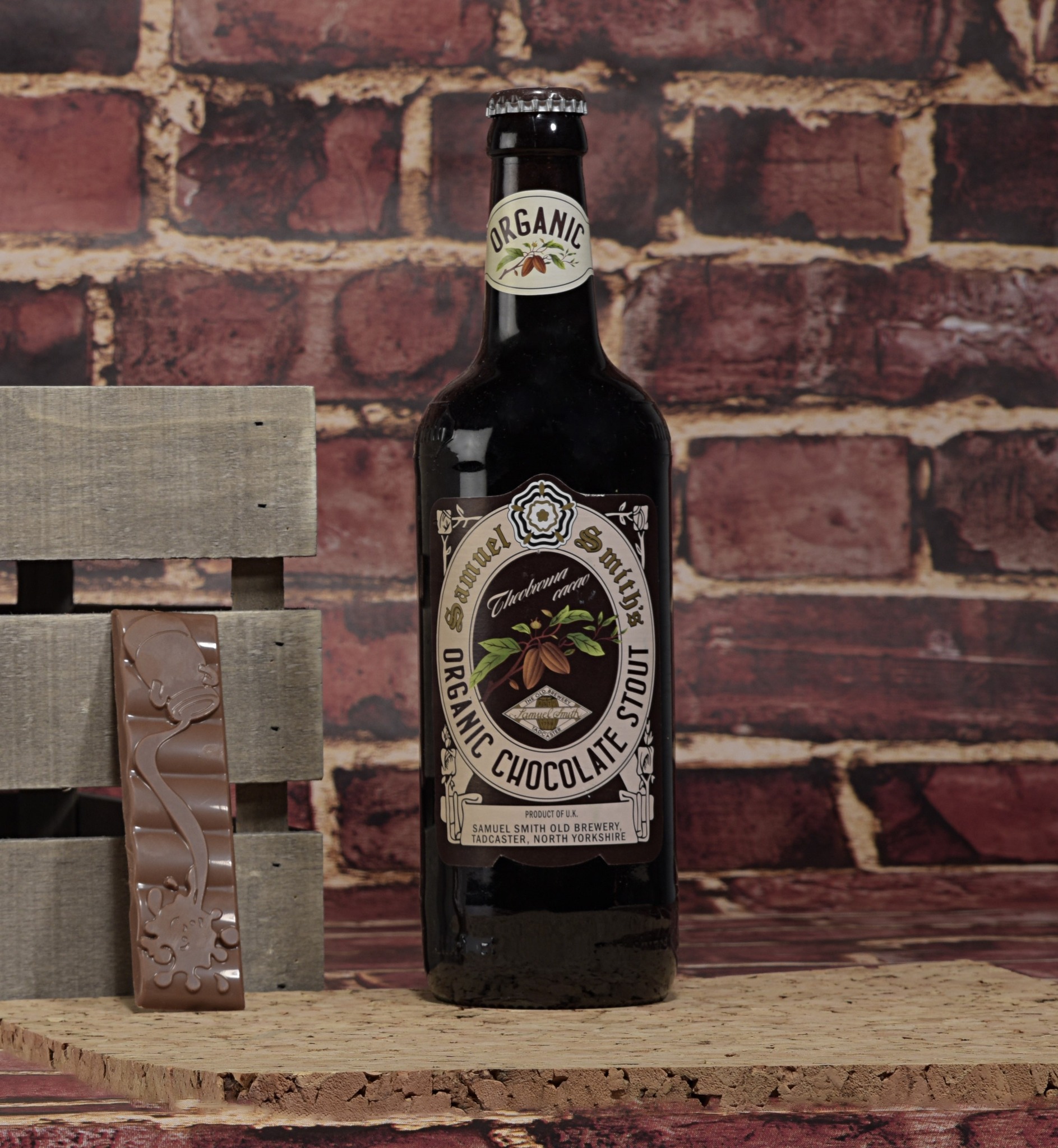 Samuel Smith organic chocolate stout in front of brick wall.