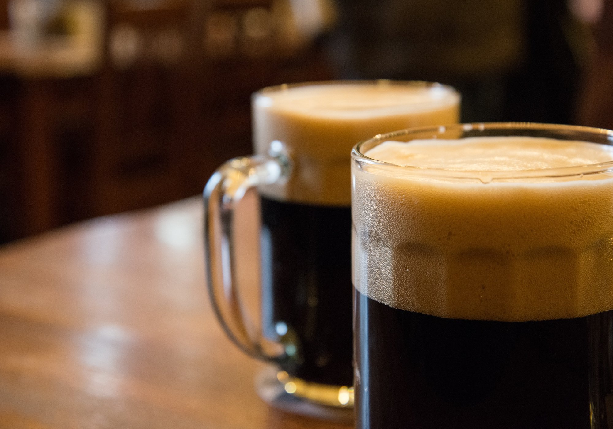 two dark beers in stein glasses on table