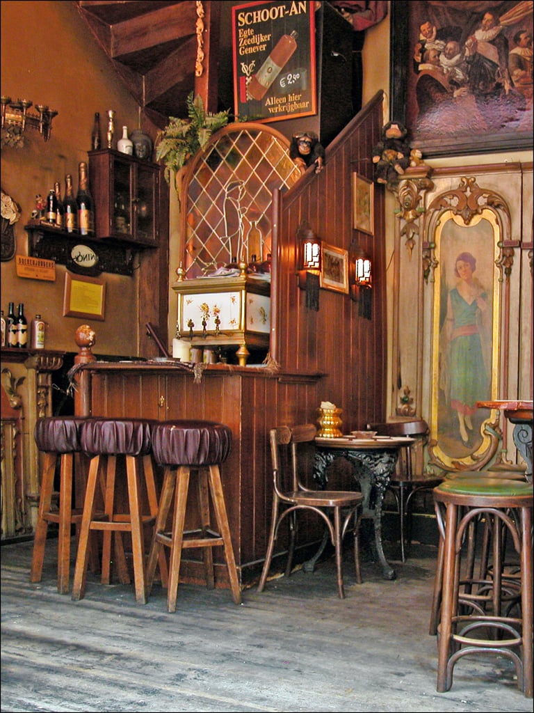 Wooden interior of In't Aepjen, with barstools and vintage wall art.