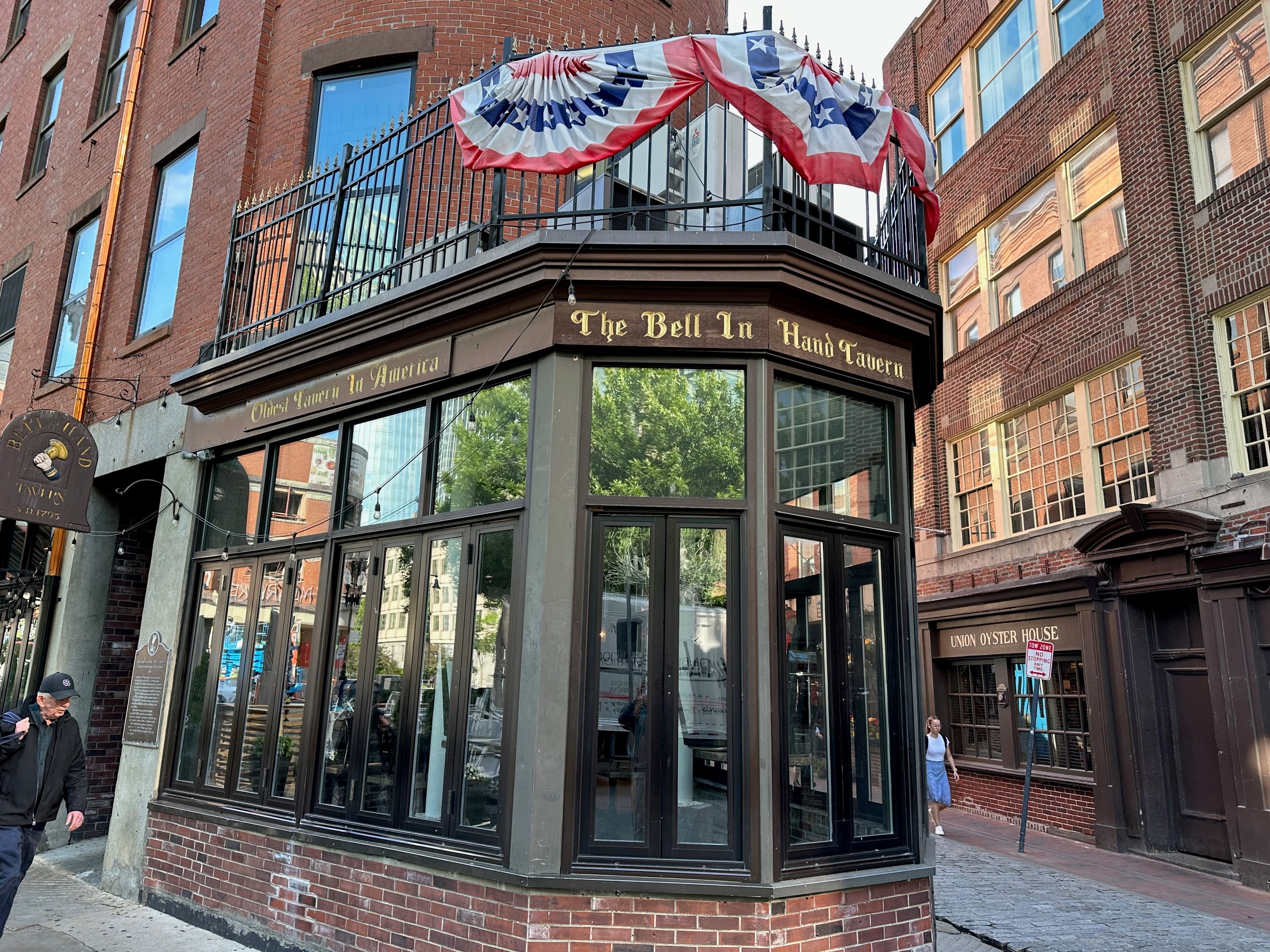 The exterior of the Bell in Hand Tavern Bar building, the oldest bar in Boston, as viewed from a street corner.