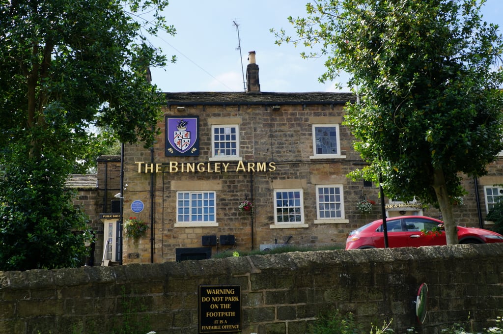 Exterior of The Bingley Arms with a bar crest and stone exterior.