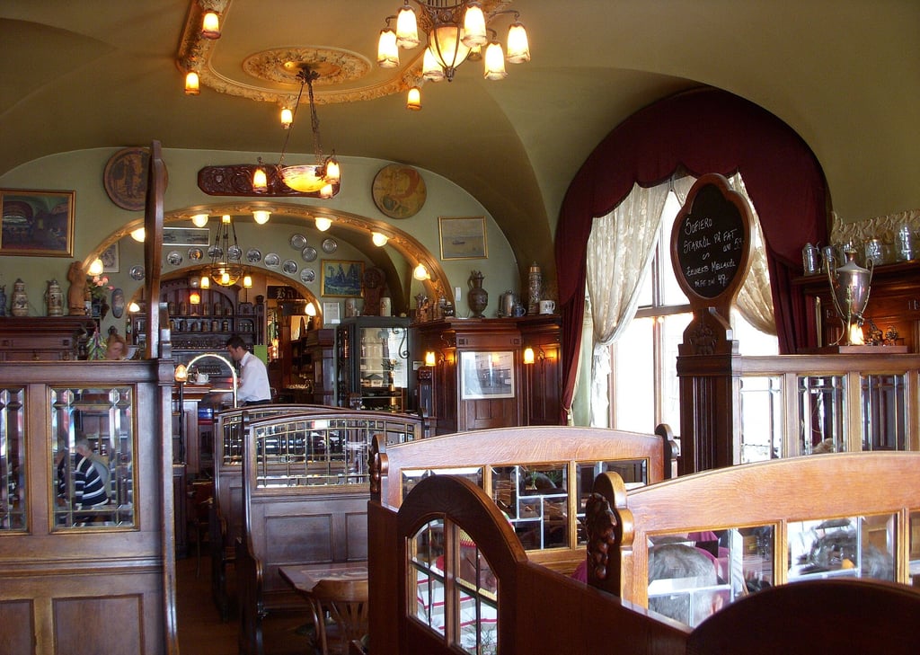 The warmly lit interior of Zum Franziskaner, with wooden seating and arched ceilings.