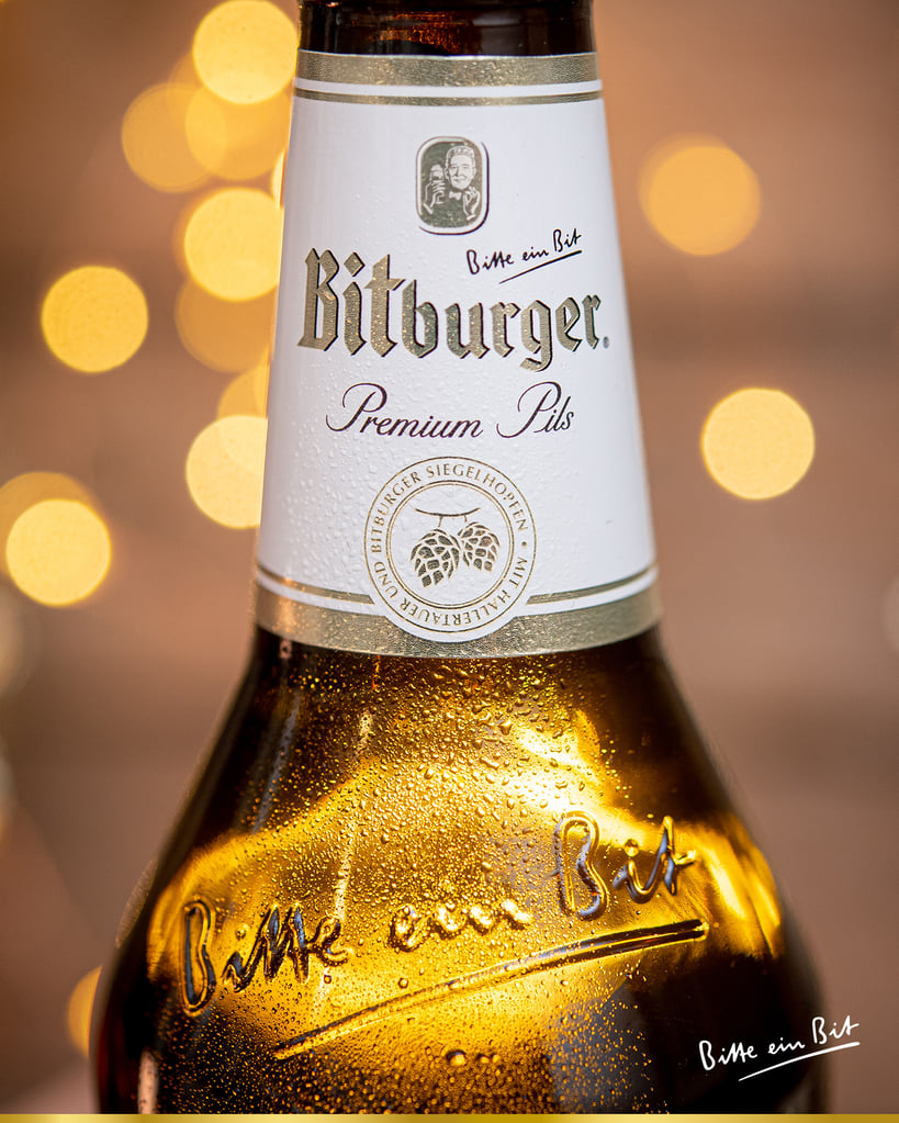 Bitburger Premium Pils bottle with lights behind.