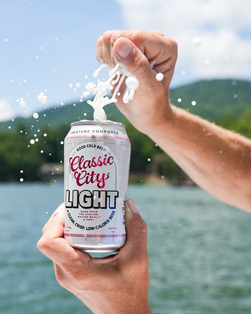 creature comforts classic city light can being cracked open on a lake