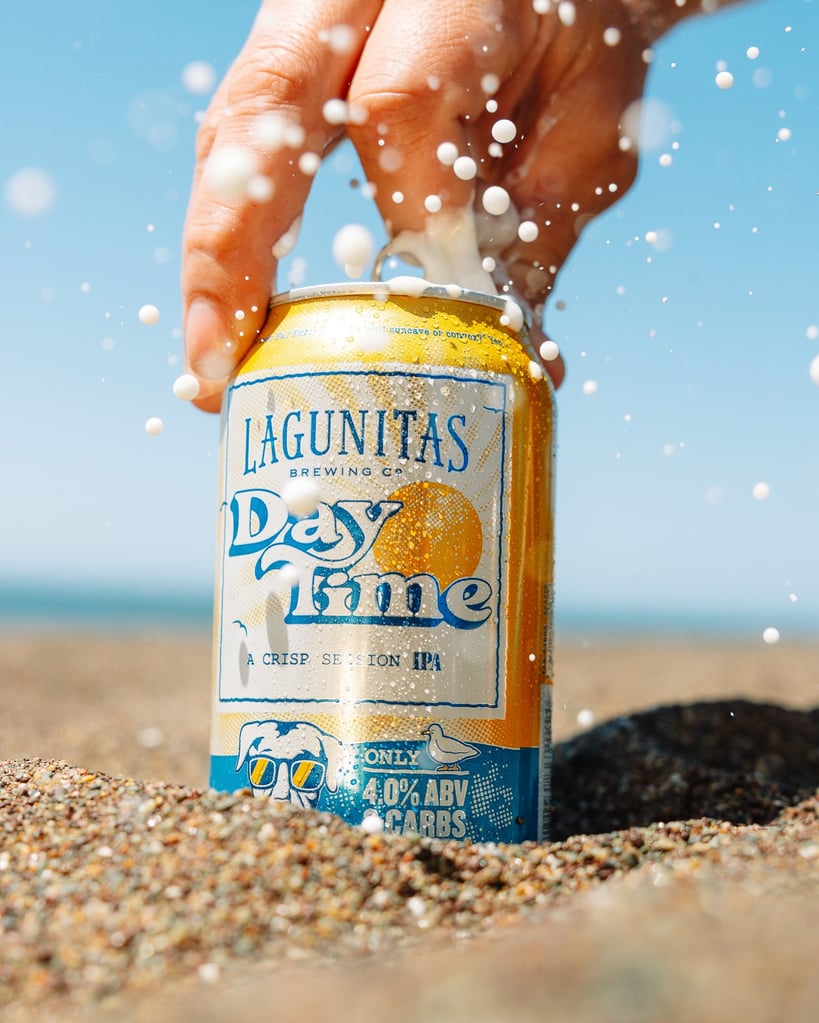 lagunitas daytime ipa being opened on a sandy beach