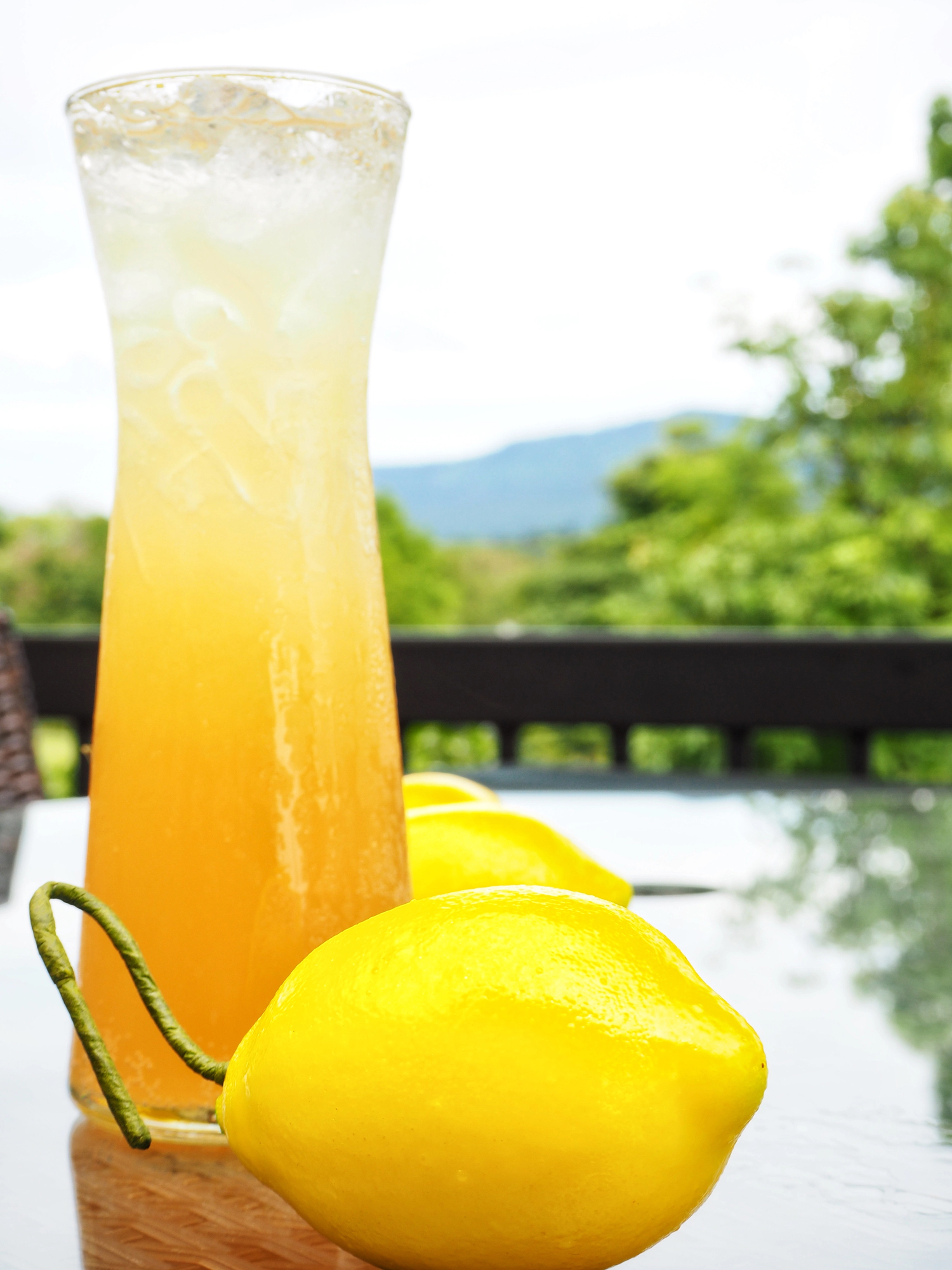 The original porch rocker drink in a pitcher on a table outdoors with lemons.