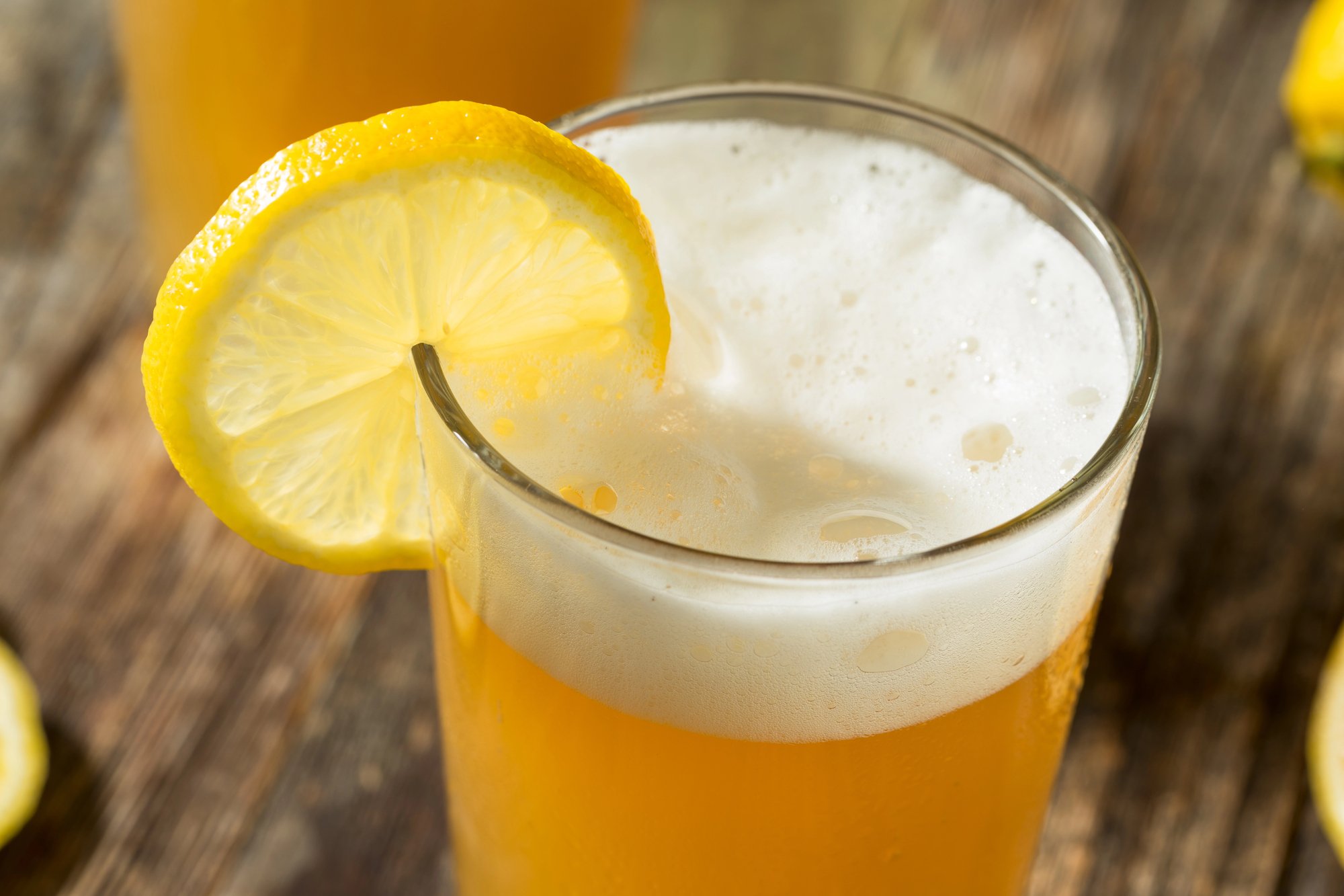 A lemon-rimmed porch drink in a glass outdoors on a wooden table.