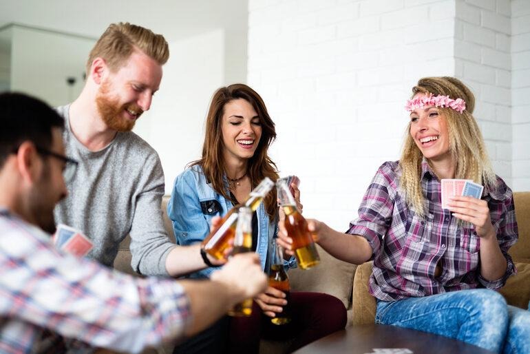 Friends playing cards and enjoying craft beer during a lively indoor game night.