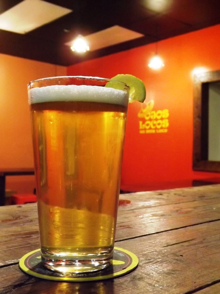 Pint of Lucky Star’s Ojos Locos with lime wedge sitting on a table at Lucky Star Brewery