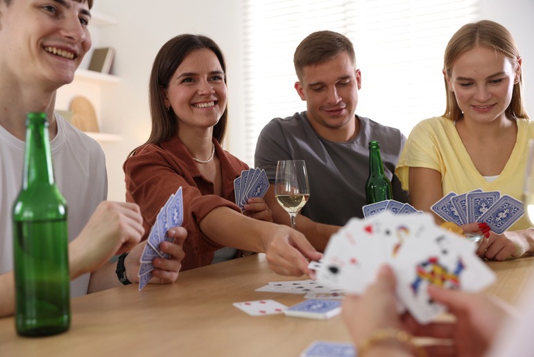 Friends gathered around a casino-style gaming table on a relaxed afternoon with beers.
