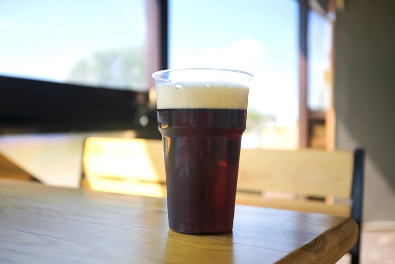 A pint of dark budget beer with a creamy head on a wooden table, illustrating the high-gravity brewing process behind affordable, high-alcohol brews.