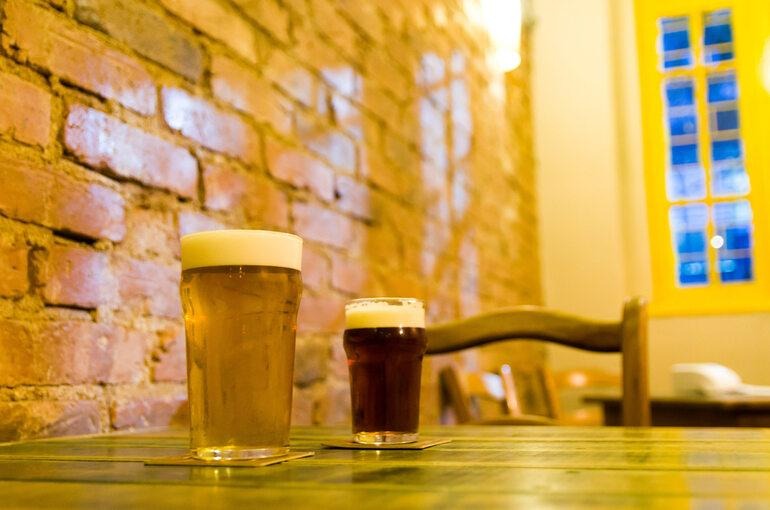 Two glasses of golden craft beer on a wooden shelf, representing Bratislava's hidden breweries, local taprooms, and authentic beer culture.