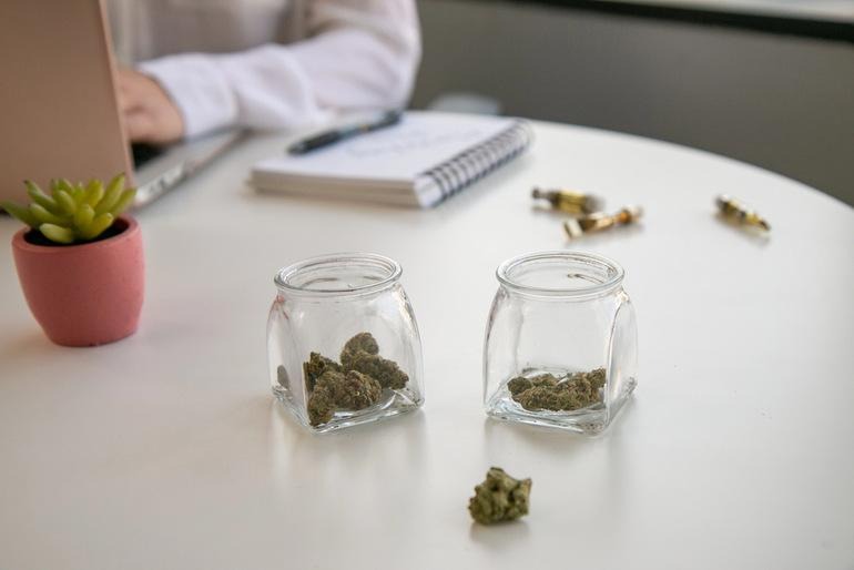 Medical cannabis flower stored in labeled glass jars on a desk beside a laptop and notebook, representing organized record-keeping throughout a medical cannabis journey in Orlando.
