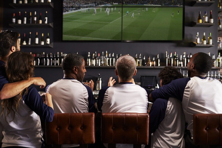 Friends watching a match together in a bar while enjoying drinks.
