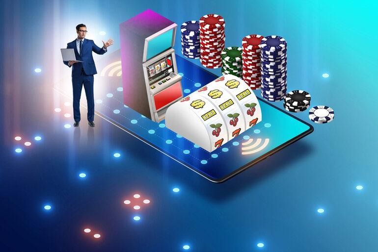 3D illustration of a businessman using a laptop beside a smartphone with casino chips and a slot machine.