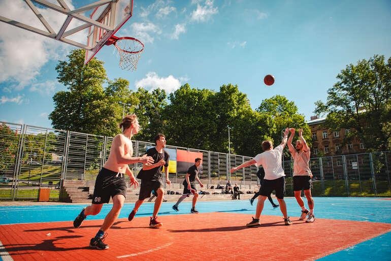 Young men playing street basketball on an outdoor court, illustrating the psychology behind the world's most popular sports.