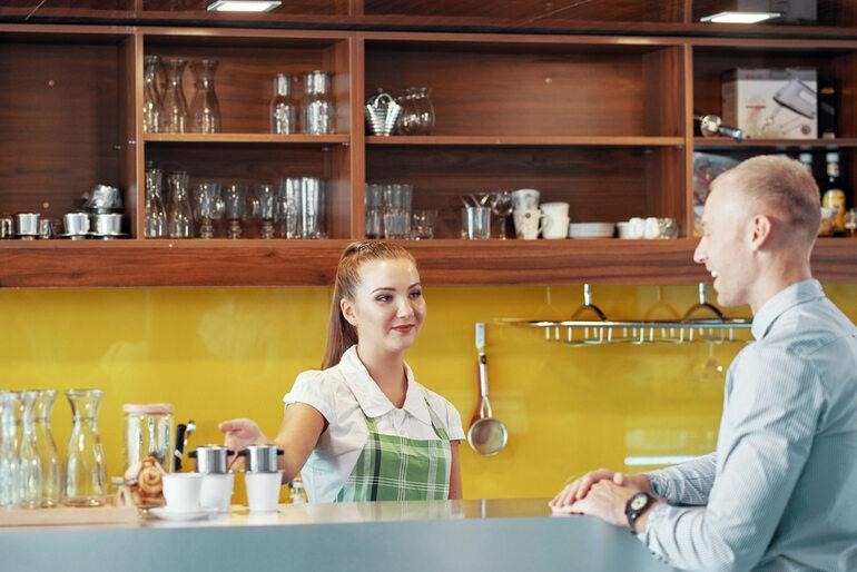 Customer service woman standing at a hospitality counter assisting a customer with a friendly, professional approach.