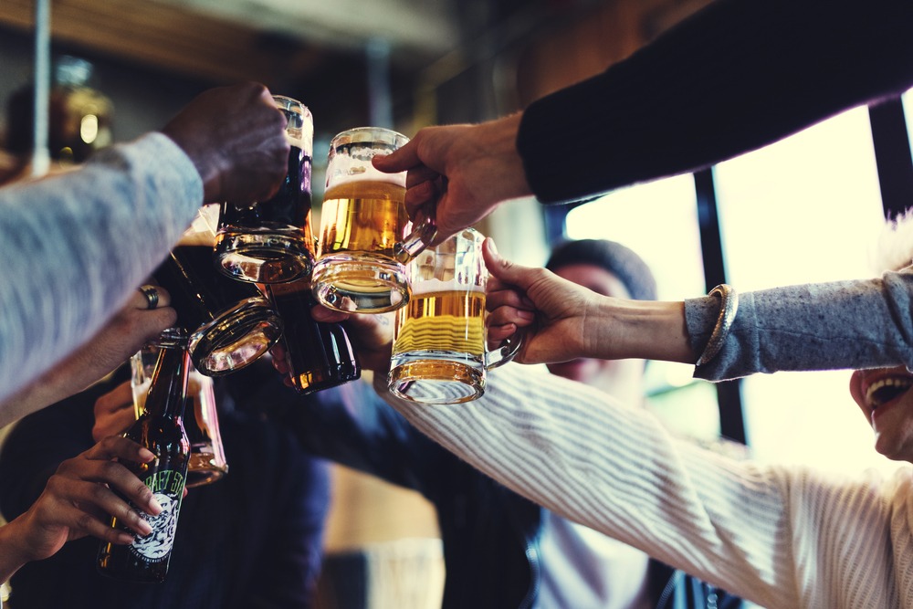 A diverse group of friends clinking beer glasses and bottles together in a toast, highlighting community and social brewery culture.