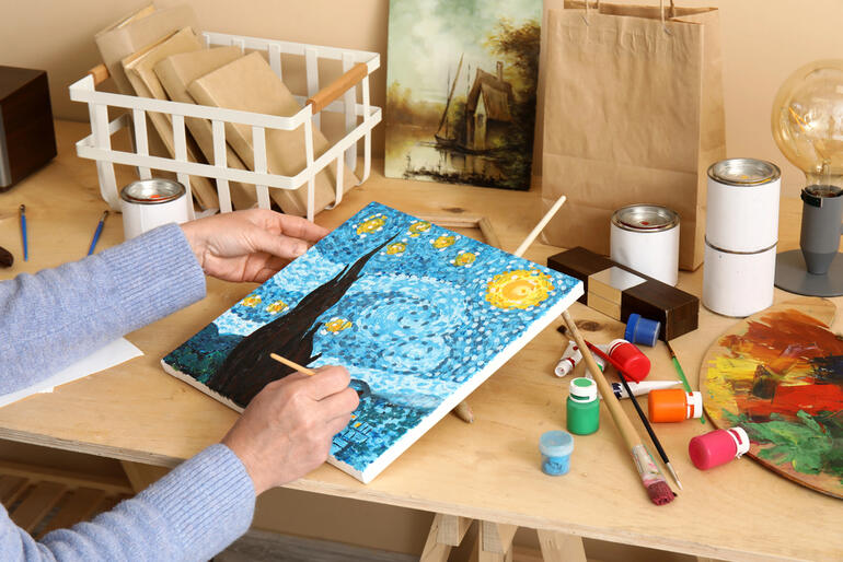 Woman happily painting on canvas while exploring creative hobbies.