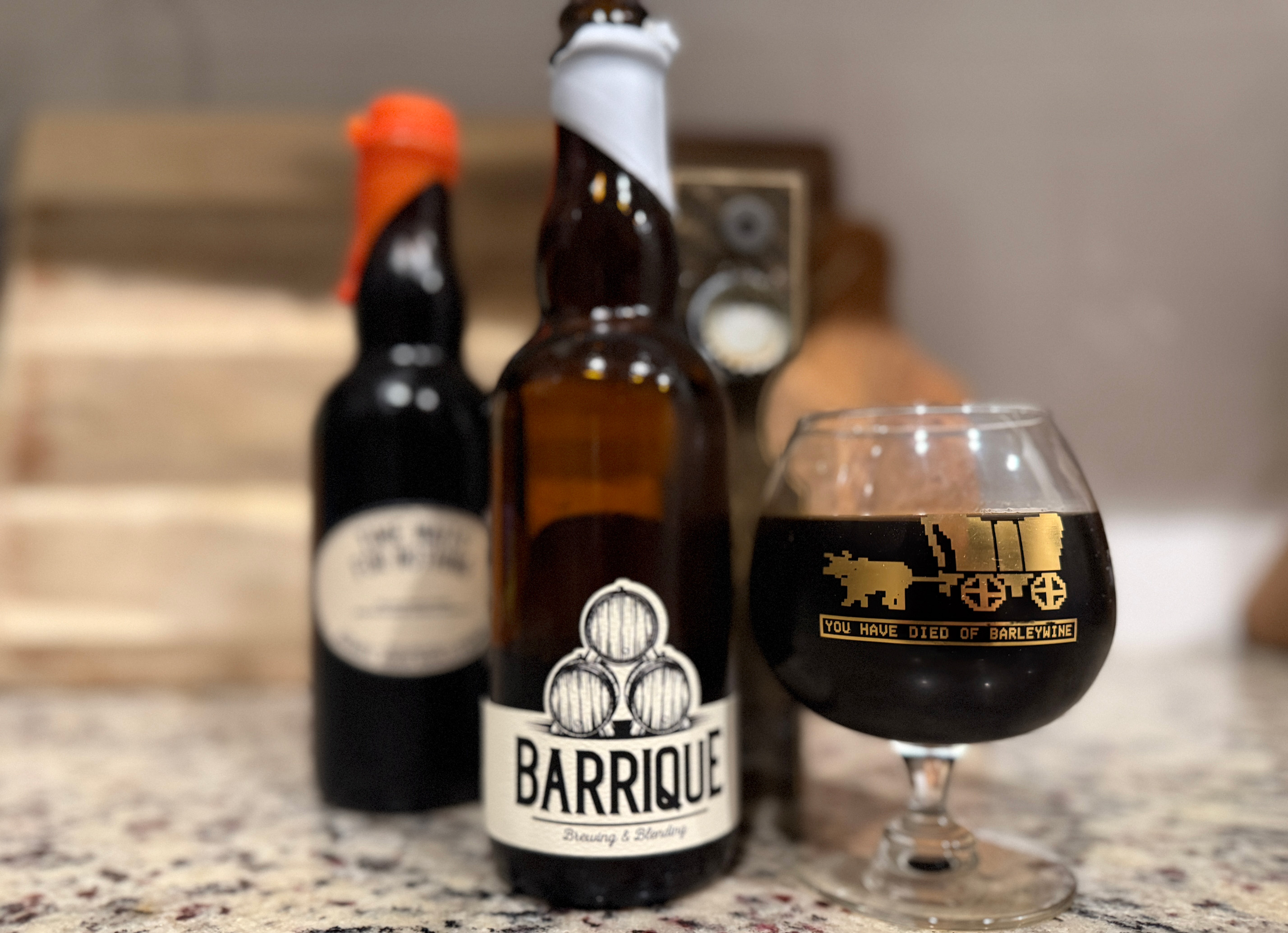 Review image of Barrique's silver wax Echo in the Void Barleywine, with Time Waits for Nothing in the background. Poured into a "You've Died of Barleywine" Glass to Mouth Snifter.