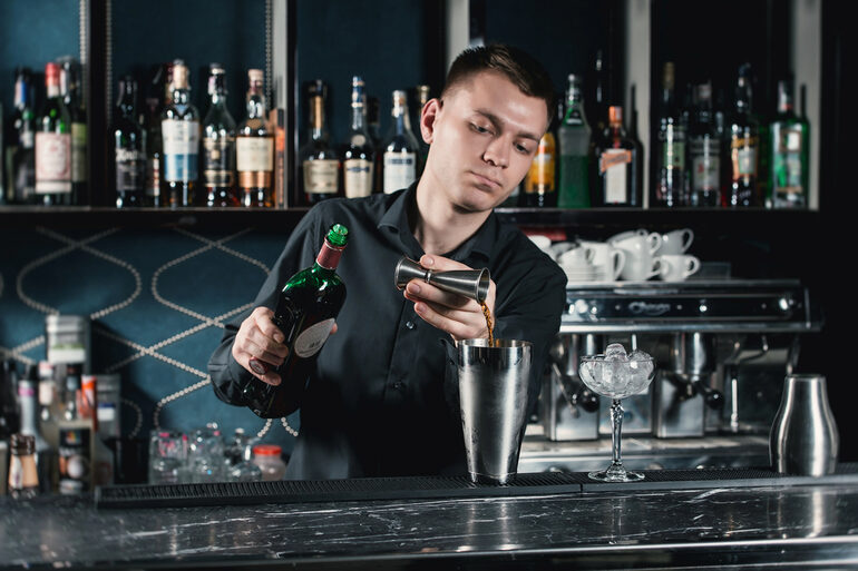 Bartender making a Cocktail pouring fluid into a glass