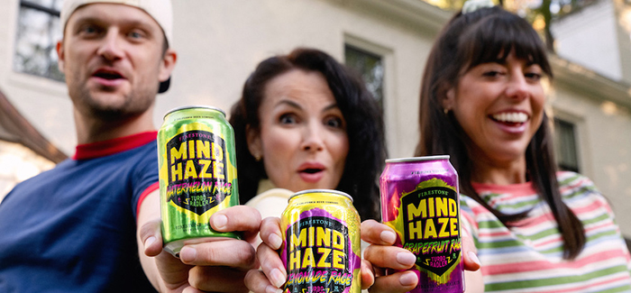 Three people hold out cans of Firestone Walker's Mind Haze Rage.