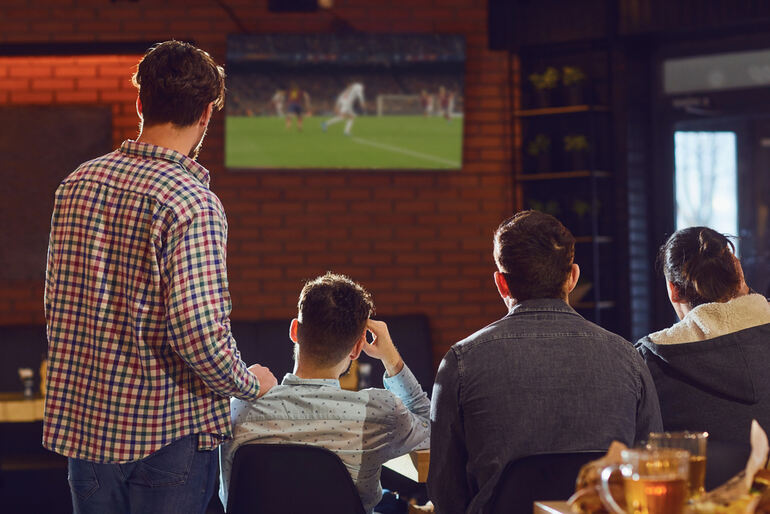 Friends watching football with beer in a taproom.